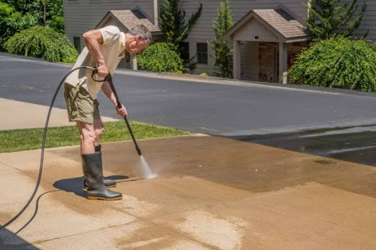 Homeowner pressure washing driveway to remove dirt and stains